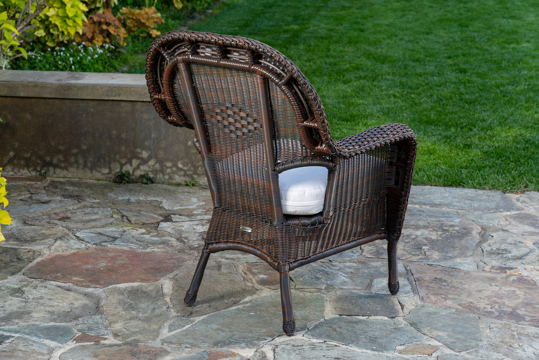 Rear view of a chair from Tortuga Outdoor Sea Pines 5-Piece Outdoor Wicker Dining Set - Java on a stone patio.