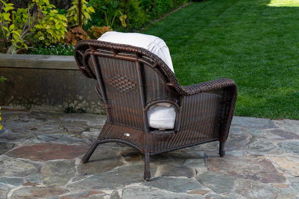 The back of the Tortuga Outdoor Sea Pines 6-Piece Loveseat Set - Java club chair with all-weather resilience sitting on a stone patio.