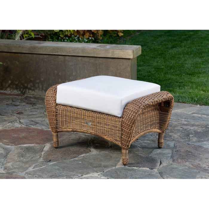 The ottoman from Tortuga Outdoor Sea Pines 3-Piece Outdoor Wicker Seating Set - Mojave on a stone patio.