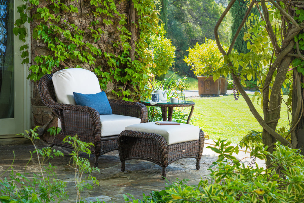 A Tortuga Outdoor Sea Pines 3-Piece Outdoor Wicker Seating Set - Java with durable construction placed among plants and grass.