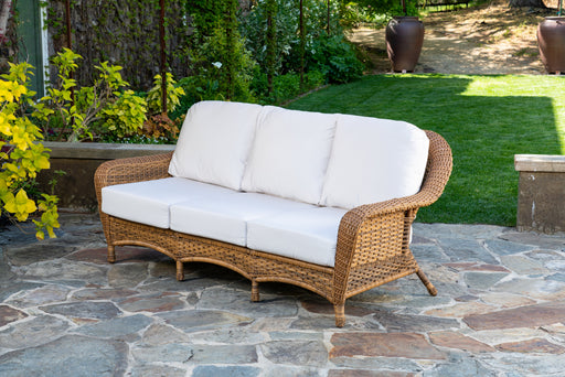 A Tortuga Outdoor Sea Pines Loveseat - Mojave on a stone patio, perfect for creating an outdoor living space.