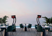 Elegant outdoor seaside dining area enhanced with Bromic Tungsten 500 Series portable gas heaters, offering comfort with a view.