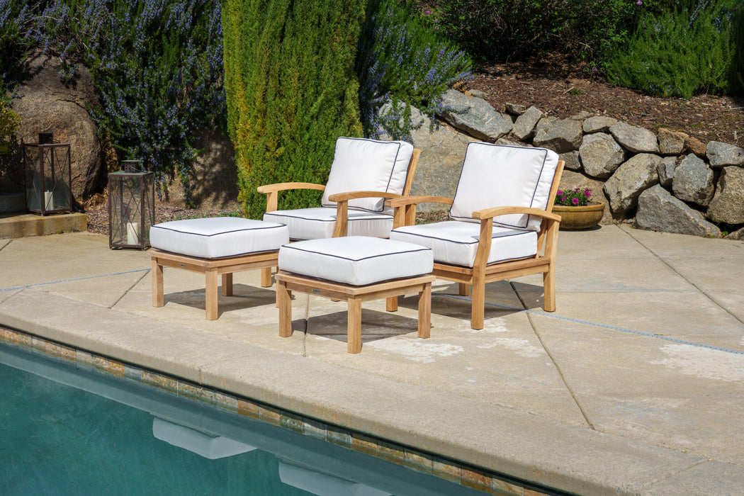 A Tortuga Outdoor 4-Piece Indonesian Teak Club Chair Set - Sunbrella Canvas Natural or Navy with durable construction is in the background near a pool.