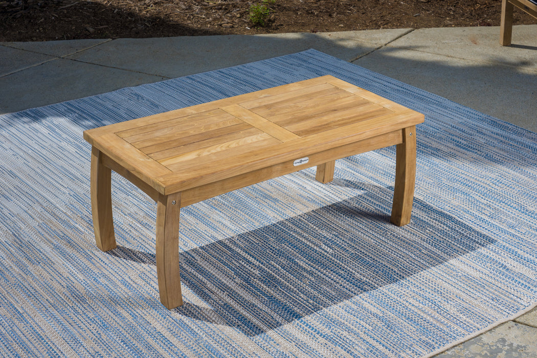 A Tortuga Outdoor 5-Piece Indonesian Teak Sofa Set - Sunbrella Canvas Natural or Navy on top of a wooden table in a patio setting.