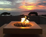 A Solus Decor Halo Low 60K BTU Fire Pit ignited with a brilliant flame against a stunning sunset backdrop, offering a picturesque and warm outdoor experience.
