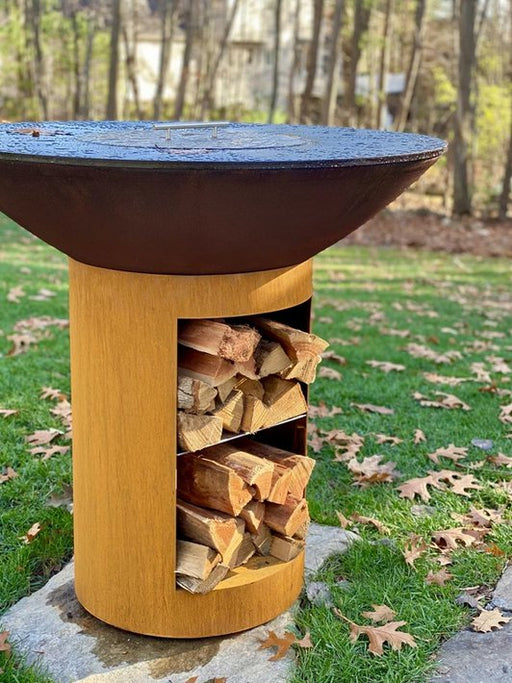 An Arteflame Classic 40" Grill with Tall Base with logs in the storage, placed in an outdoor setting.