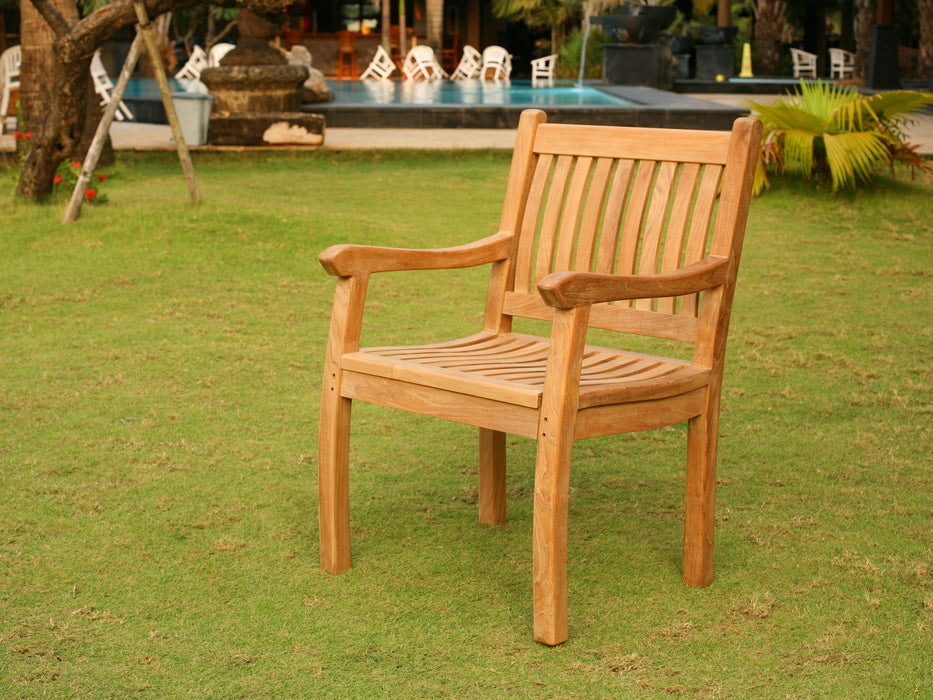 A Tortuga Outdoor Jakarta 5-Piece Dining Teak Set in a grassy area near a swimming pool.