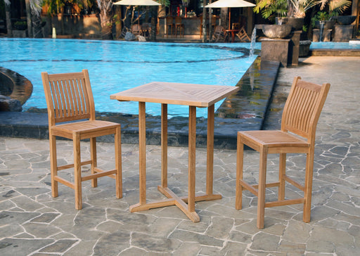 A Tortuga Outdoor Jakarta 3-Piece Teak Wood Bar Set, consisting of two chairs and a table, positioned next to a pool.