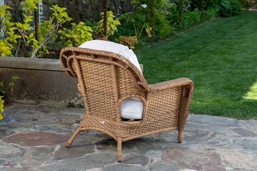 Rear view of the club chair from the Tortuga Outdoor Sea Pines 5-Piece Outdoor Wicker Conversation Set - Mojave sitting on a stone patio.