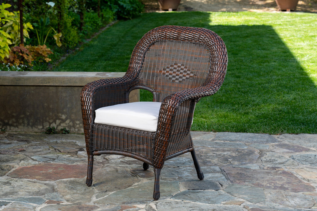 Front view of a chair from the Tortuga Outdoor Sea Pines 5-Piece Outdoor Wicker Dining Set - Java on a stone patio.