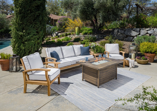 The Tortuga Outdoor 5-Piece Indonesian Teak Sofa and Fire Table Set - Canvas Natural or Navy is a durable outdoor wicker furniture set that includes a table and chairs.