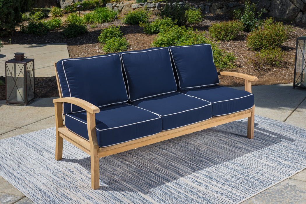 A Tortuga Outdoor 6-Piece Indonesian Teak Outdoor Sofa Set - Sunbrella Canvas Natural or Navy with durable construction and blue cushions on an all-weather resin wicker rug.