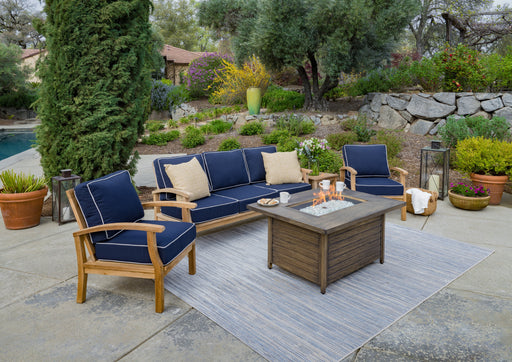 A patio with durable construction and a Tortuga Outdoor 5-Piece Indonesian Teak Sofa and Fire Table Set - Canvas Natural or Navy.