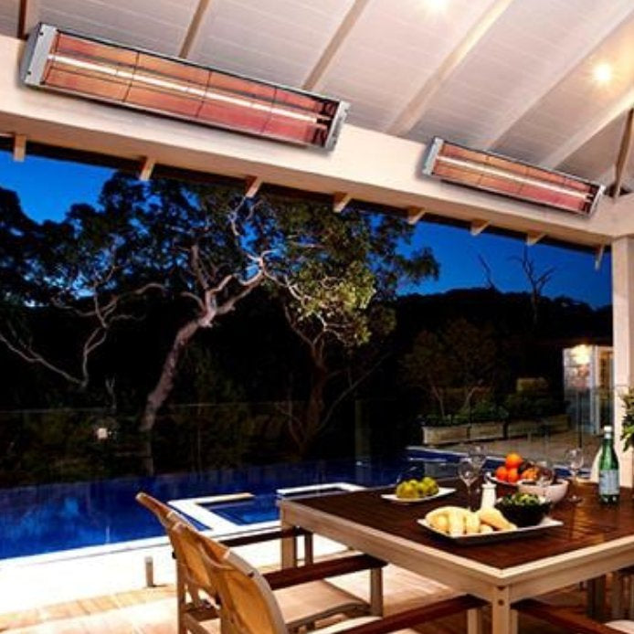 Bromic Heating Cobalt Smart-Heat 4000w electric patio heater providing a warm glow to a luxurious night-time dining experience outdoors beside a pool.