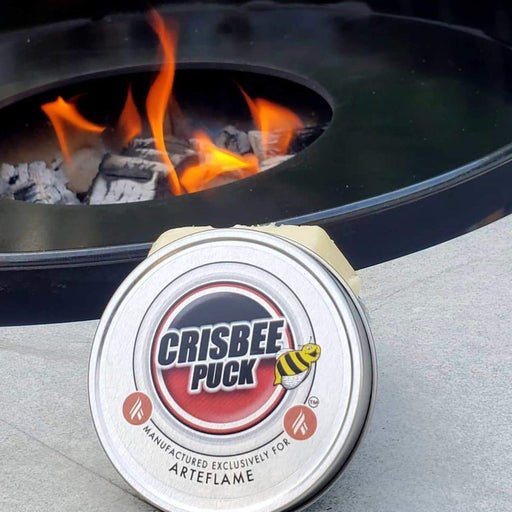 Crisbee Puck for Grill Seasoning placed near a flaming Arteflame grill insert, showcasing the product in its intended use environment.