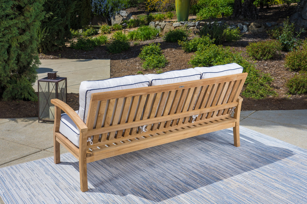 A durable Tortuga Outdoor teak outdoor sofa with cushions on a rug, designed for patio furniture.