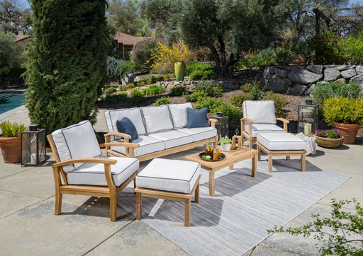 A durable Tortuga Outdoor teak patio furniture set with white cushions.