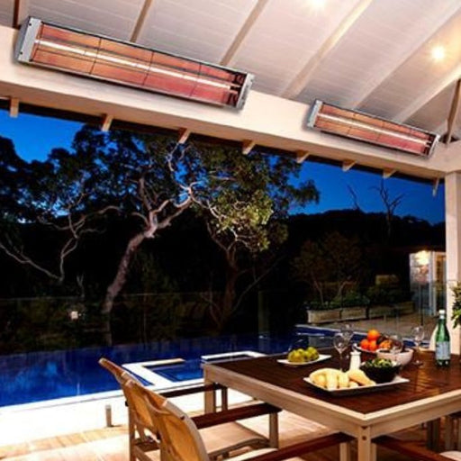 Warm and inviting outdoor dining scene by the pool at night, illuminated and heated by the Bromic Heating Cobalt Smart-Heat 6000w electric patio heater.
