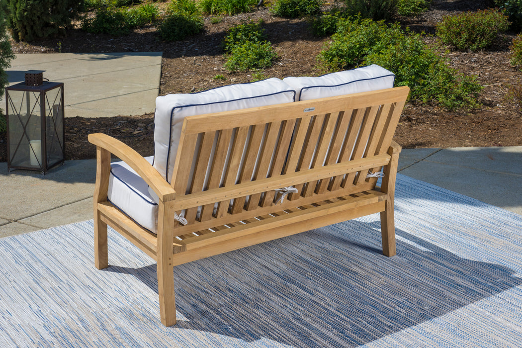 A durable Tortuga Outdoor teak outdoor lounge chair on a rug.