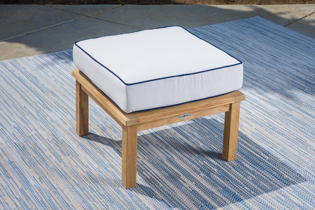 A Tortuga Outdoor teak ottoman with a durable construction and a white and blue cushion.