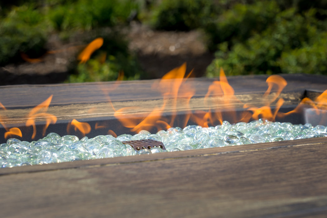 A Tortuga Outdoor 5-Piece Indonesian Teak Sofa and Fire Table Set - Canvas Natural or Navy with a fire in it.