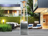 Stainless steel Vesta Flame Tower Heater in a garden patio setting
